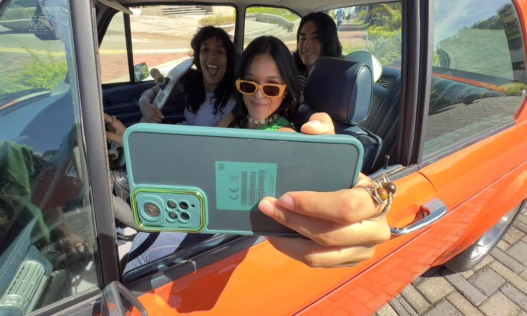 Tres jóvenes se toman una selfie con un celular desde un auto