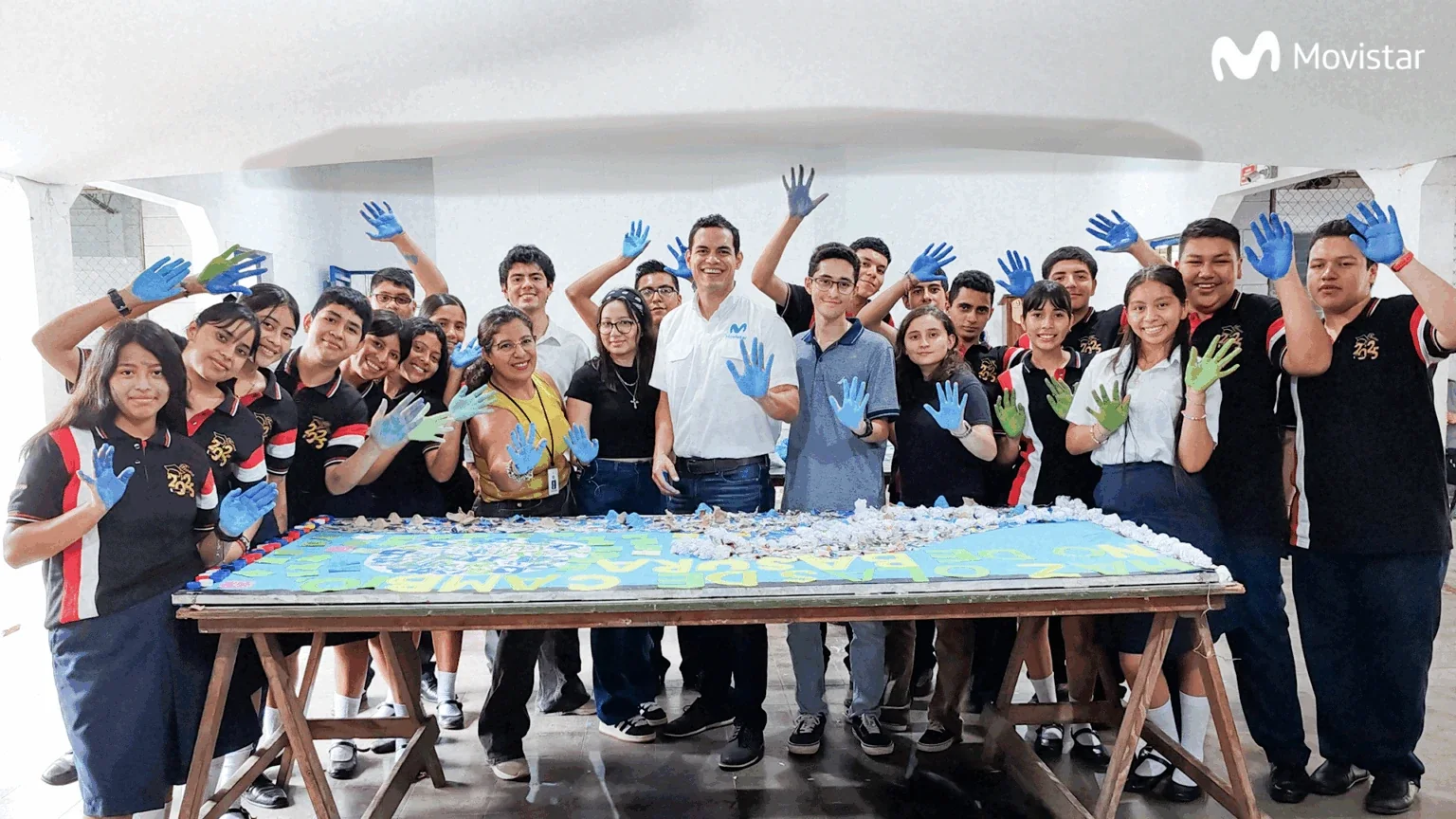 Estudiantes y voluntarios con las manos pintadas junto al mural colaborativo sobre reciclaje