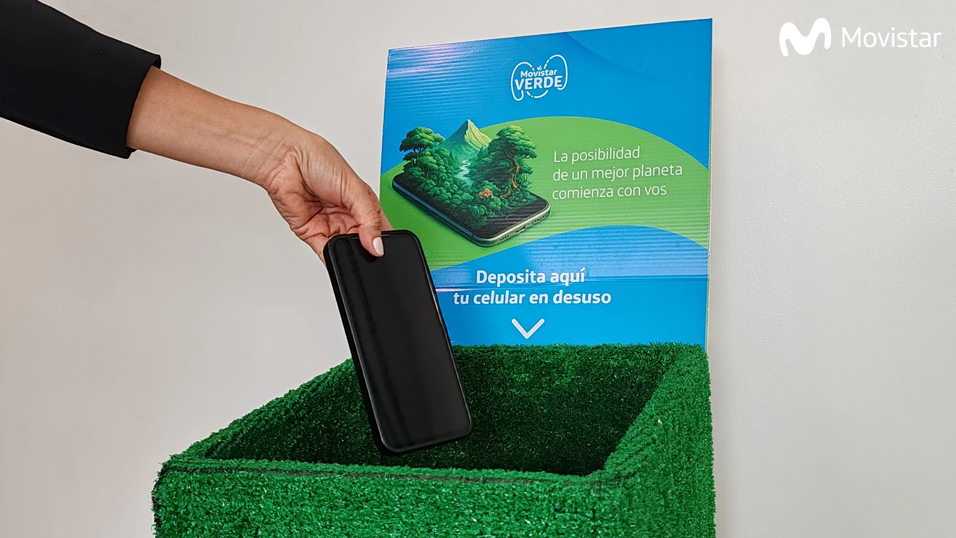 Una persona deposita un celular en desuso en un punto de recolección de Movistar